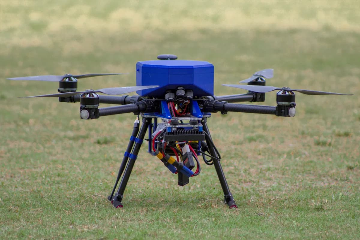 The blue quadcopter on grass, front three-quarter view